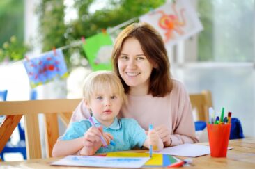 Cute little boy drawing and painting with colorful markers pens at kindergarten