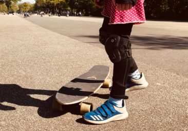 Schulkind auf einem Skateboard bei sonnigem Wetter